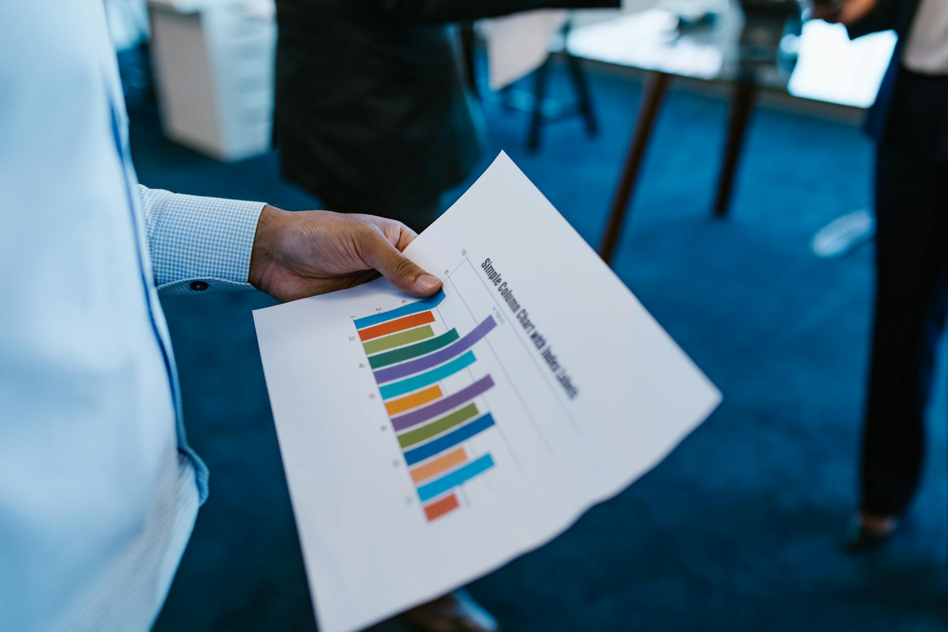 Hand holding a printed bar chart report in a business meeting