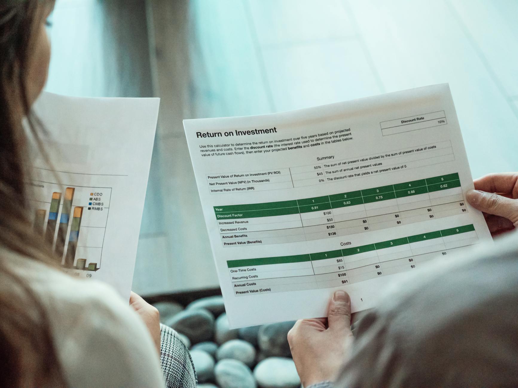Two people reviewing marketing performance documents and ROI charts.