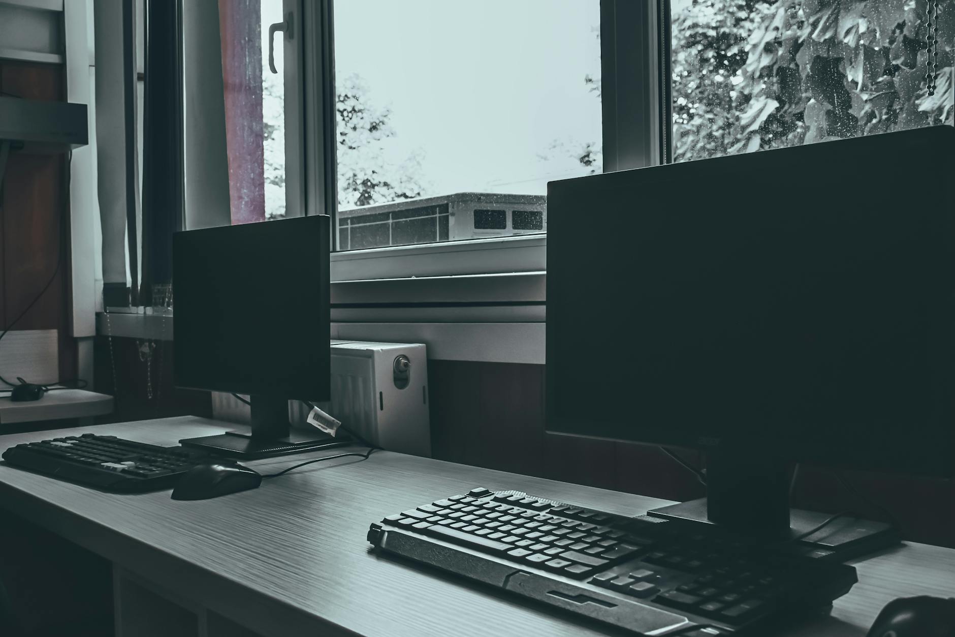 Modern desk with dual monitors near a window in an office
